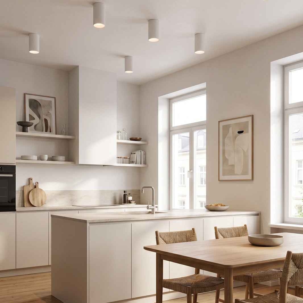 Cuisine blanche ouverte avec spots tube Tubélis au plafond au-dessus du plan de travail et d'une table en bois