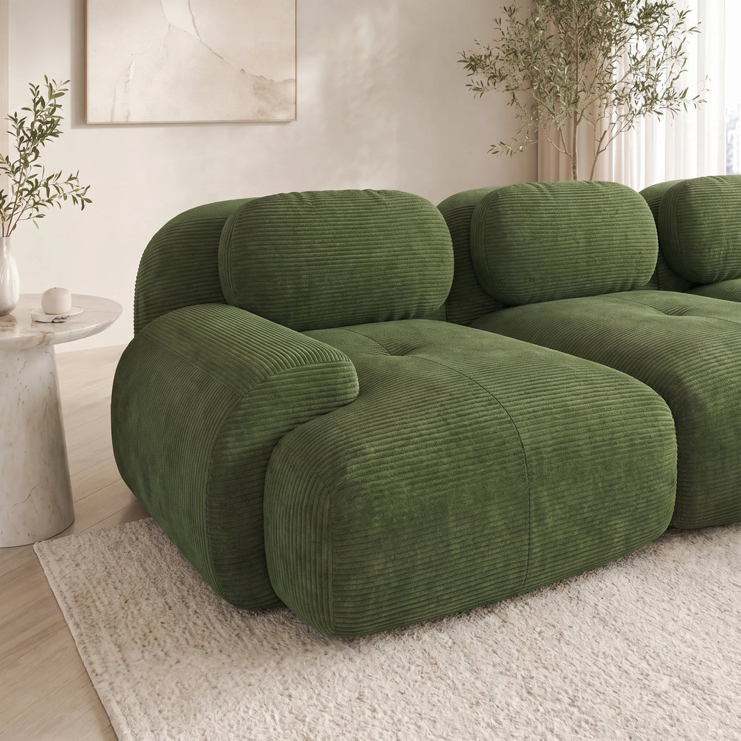 Canapé d'angle modulable en velours côtelé vert dans un salon lumineux, côtes du tissu visibles sur l'assise et l'accoudoir