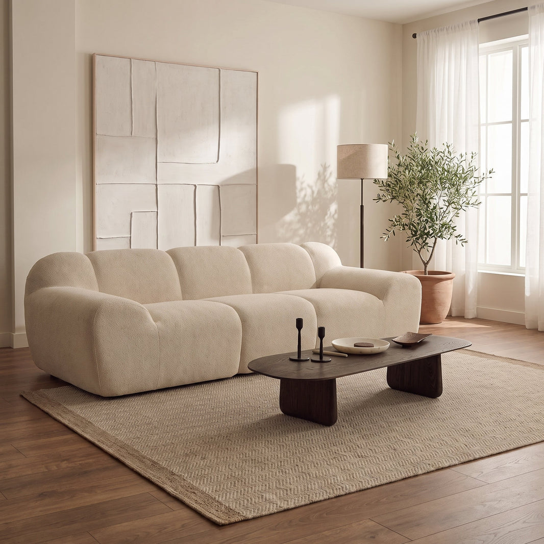 Canapé cloud 3 places en chenille beige aux volumes arrondis dans un salon lumineux, sur un tapis en jute