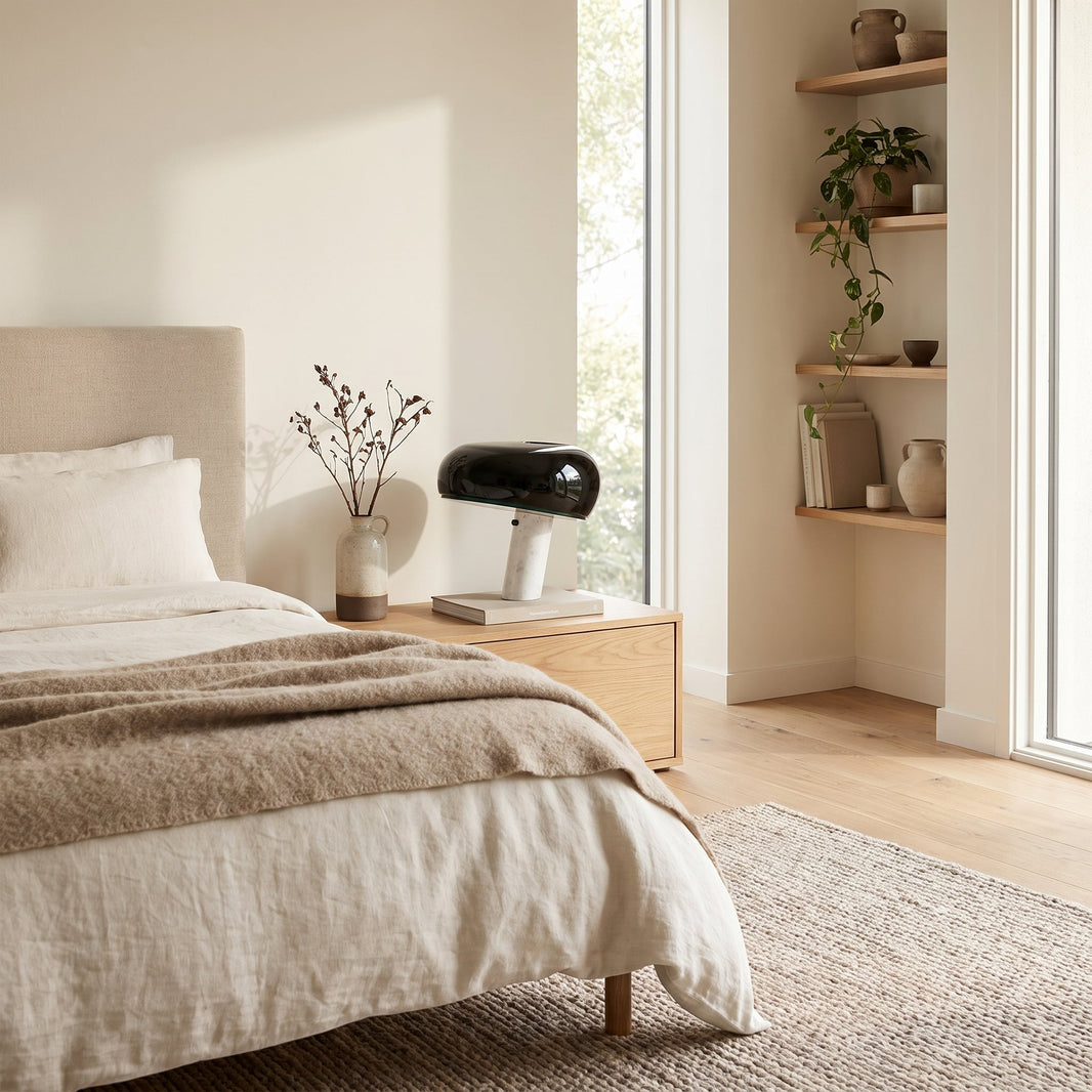 Lampe de chevet champignon à abat-jour noir et pied en marbre posée sur une table de nuit en bois dans une chambre claire
