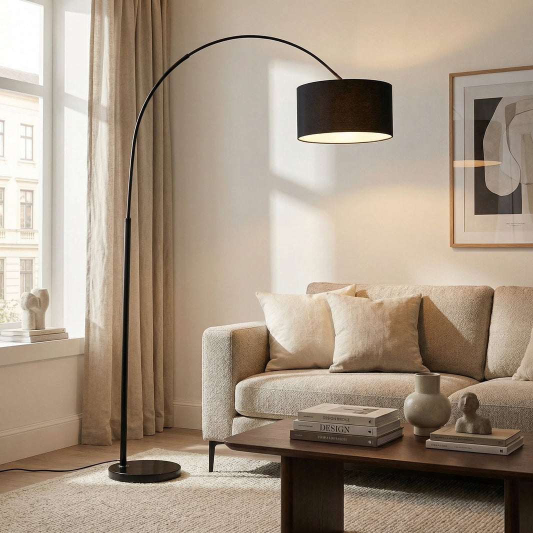 Salon lumineux avec un lampadaire arc noir dont l'abat-jour cylindrique s'avance au-dessus d'un canapé beige
