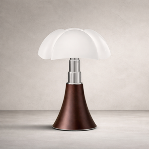 Lampe de table style champignon, abat-jour blanc à pétales, tige métal argent, base conique marron sur fond neutre.