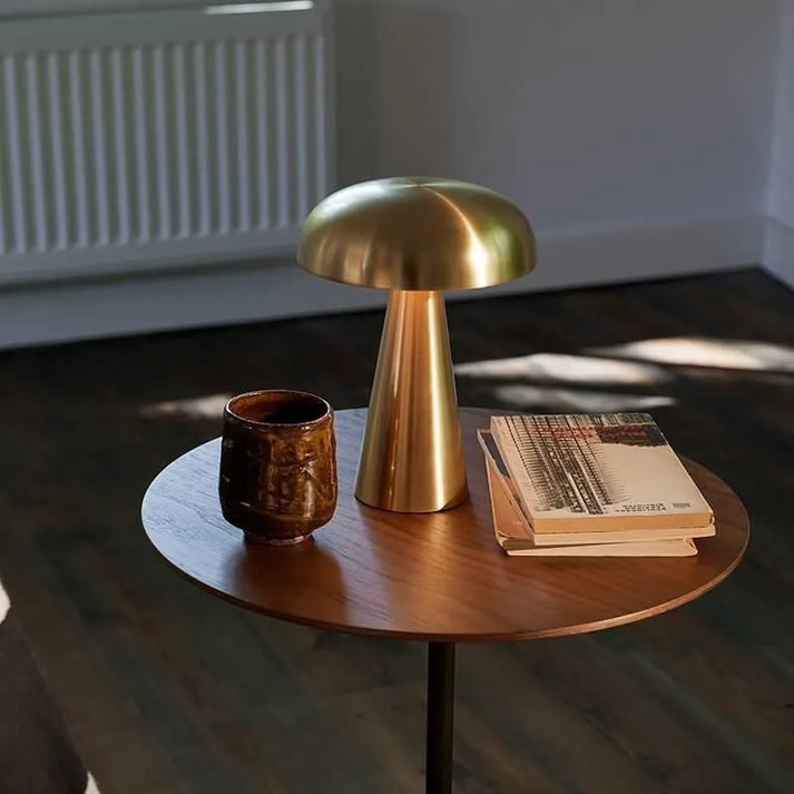 Lampe Fuméa dorée posée sur un guéridon en bois