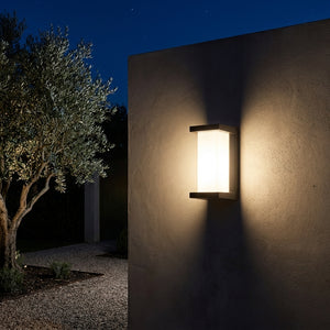 Applique murale extérieure noire Noctéa (format vertical) sur un mur de jardin la nuit, lumière chaude