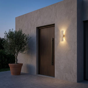 Applique extérieure en travertin Stélia à côté d'une porte d'entrée en bois, lumière chaude au crépuscule