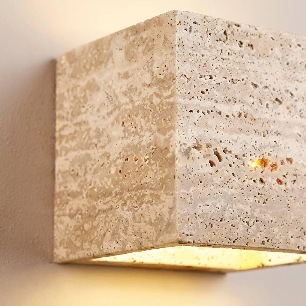 Gros plan sur la texture poreuse du travertin de l'applique murale cube Luminosa