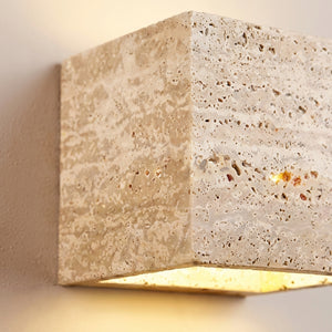 Gros plan sur la texture poreuse du travertin de l'applique murale cube Luminosa