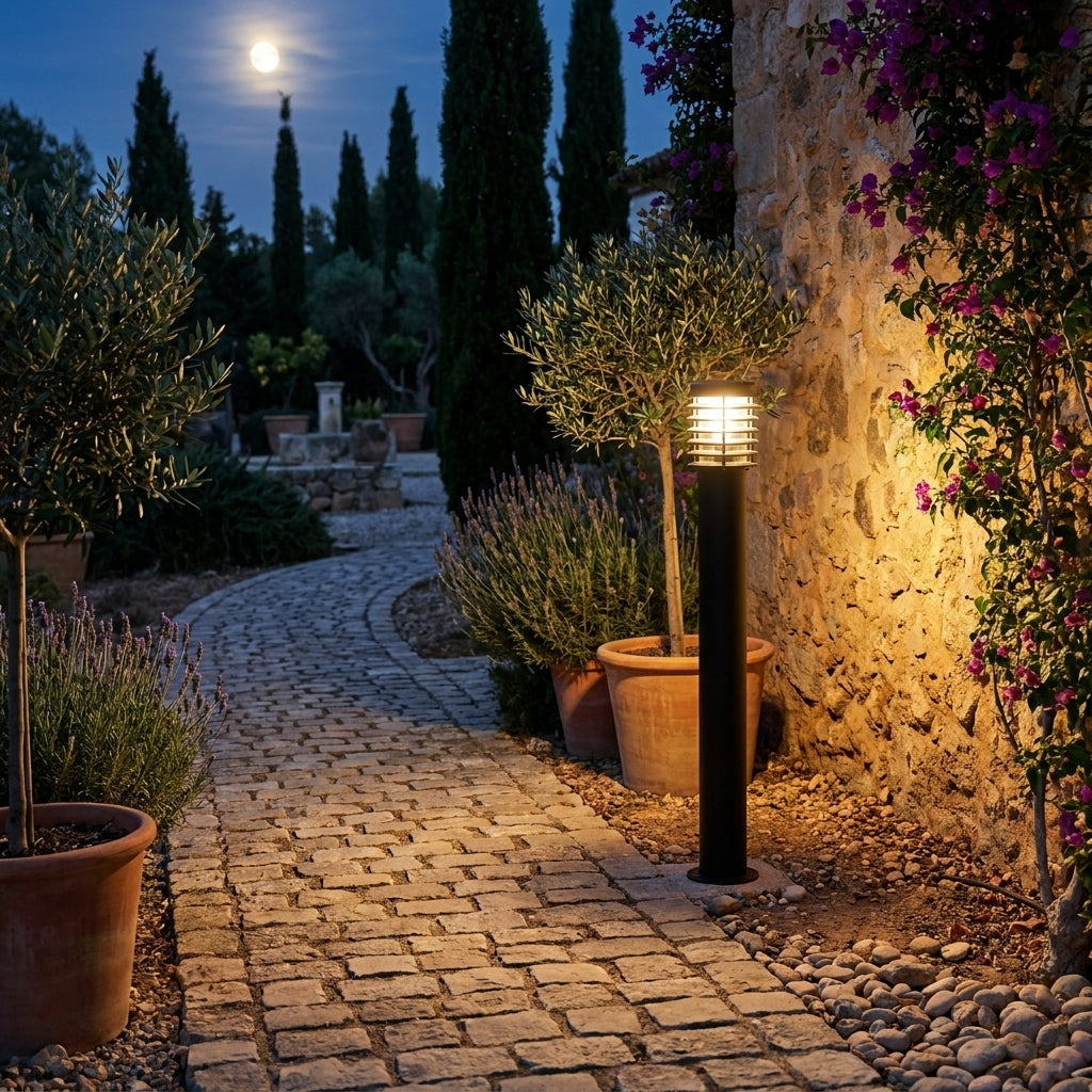 Lampadaire d'extérieur Noctis bordant une allée pavée dans un jardin méditerranéen, lavande et mur en pierre