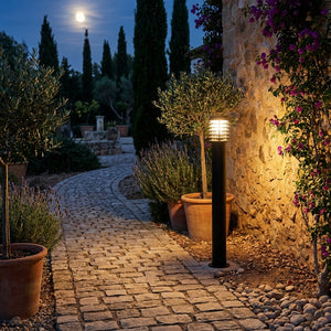 Lampadaire d'extérieur Noctis bordant une allée pavée dans un jardin méditerranéen, lavande et mur en pierre