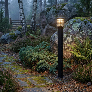 Lampadaire d'extérieur Noctis dans un jardin nordique parmi fougères et rochers moussus