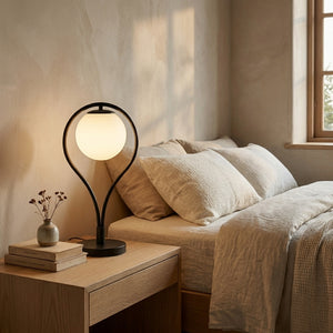Lampe de table Liora sur une table de chevet en chêne dans une chambre en lin, lumière du soir