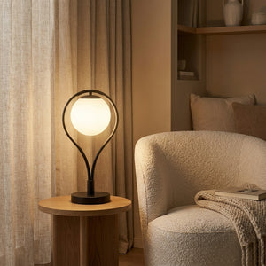 Lampe de table Liora sur un guéridon près d'un fauteuil bouclé, ambiance chaleureuse