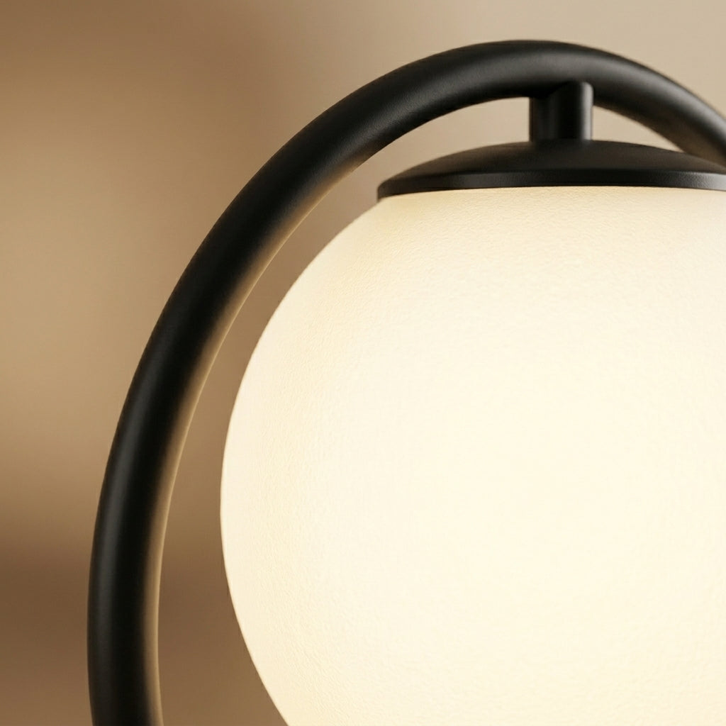 Détail du globe en verre opalin de la lampe Liora niché dans la boucle en métal noir