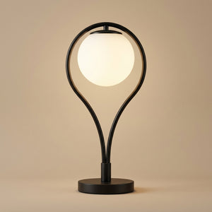 Lampe de table Liora, globe en verre opalin dans un cadre métal noir en forme de goutte, sur fond beige