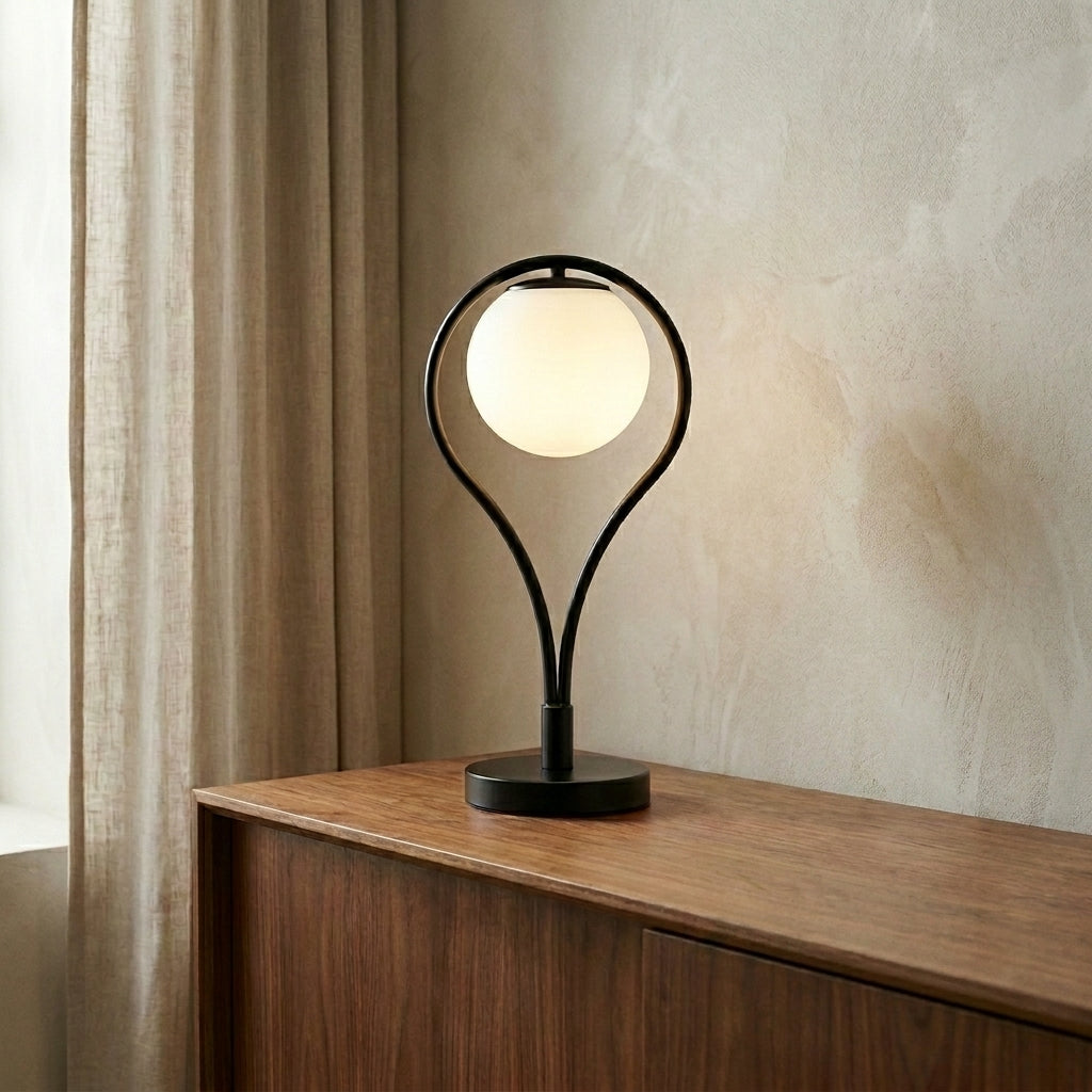 Lampe de table Liora allumée sur un buffet en noyer, lumière chaude tamisée, mur en enduit