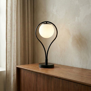 Lampe de table Liora allumée sur un buffet en noyer, lumière chaude tamisée, mur en enduit