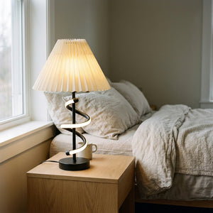 Lampe de table Hélia sur une table de chevet en chêne dans une chambre en lin, lumière naturelle