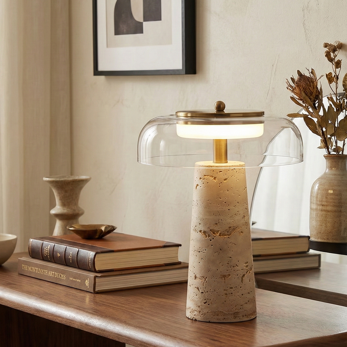 Lampe travertin et verre allumée sur une console, à côté de livres