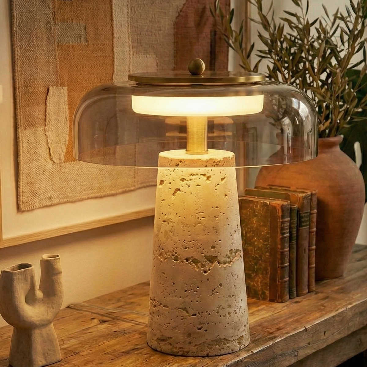 Lampe travertin et cloche de verre transparent devant un tableau